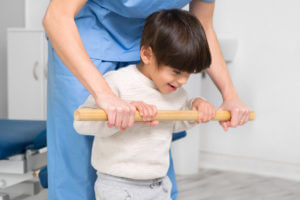 Doctor supports a children with cerebral palsy during physiotherapy treatment