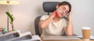 Woman having Neck and Shoulder pain in workplace, caused by cervical dystonia.