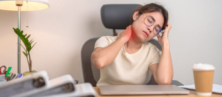 Woman having Neck and Shoulder pain in workplace, caused by cervical dystonia.